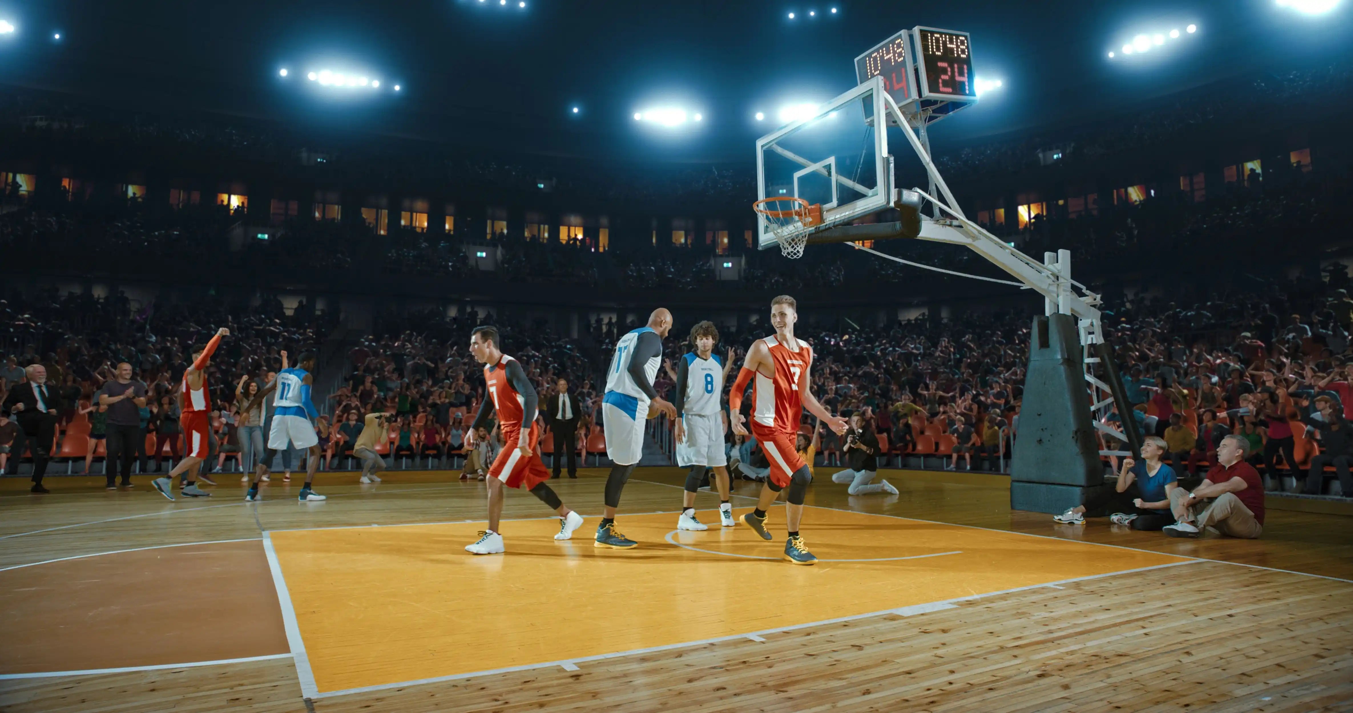 Basketball game in progress with players on the court and a crowd watching.